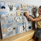 Child interacting with a wall-mounted wooden activity board with various educational elements.