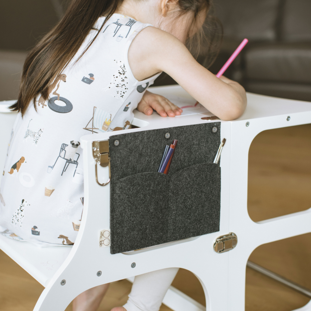 Child drawing at white Montessori-inspired desk with felt pencil case and art supplies