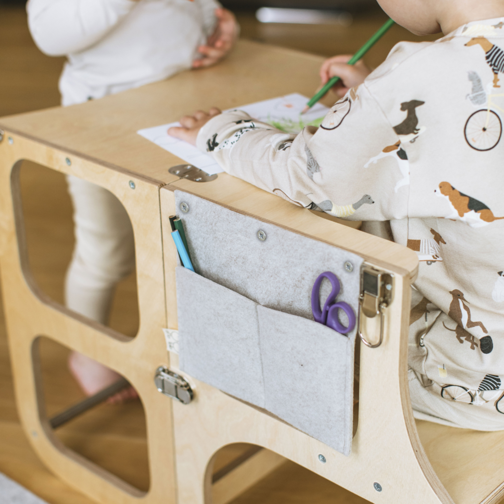 Child drawing at wooden Montessori desk with felt pencil case and school supplies