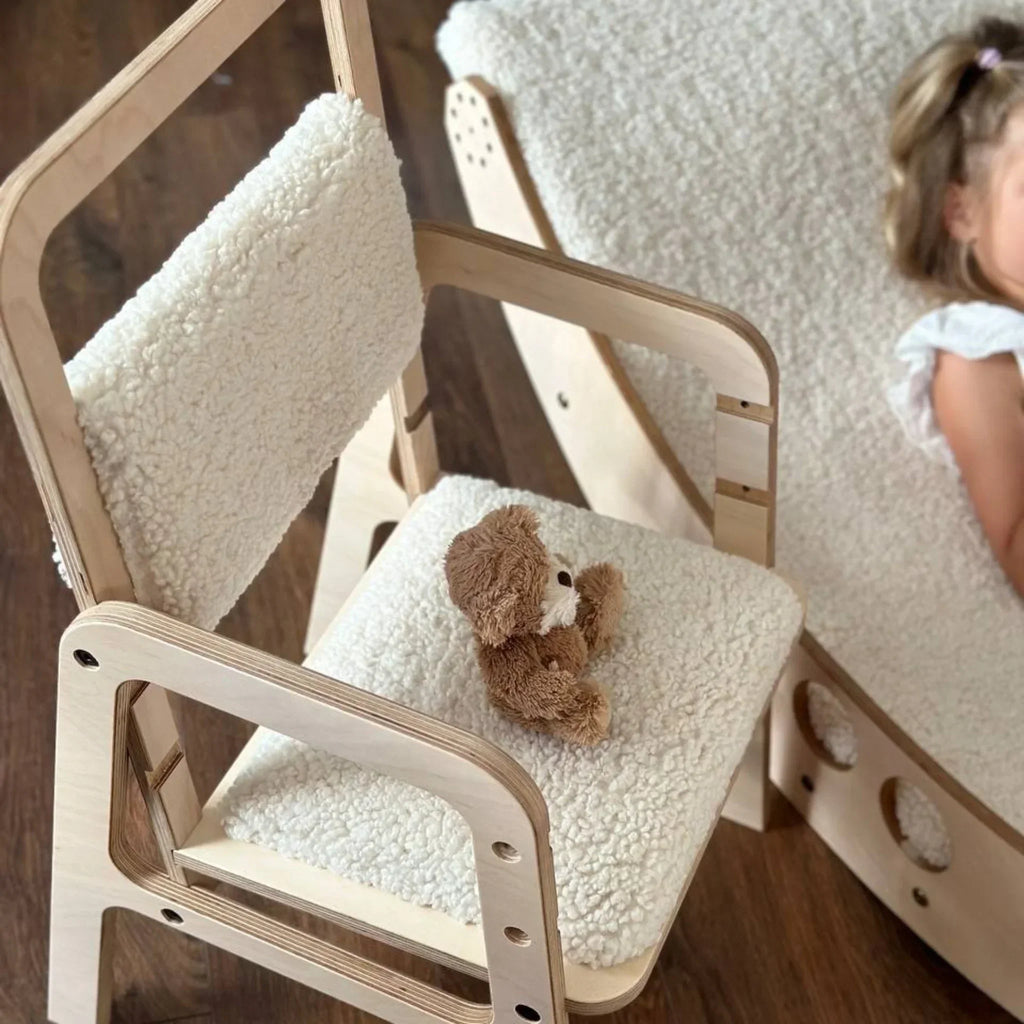 Adjustable Montessori children’s chair with soft cream padding and plush toy on wooden floor