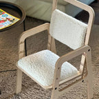 Wooden chair with white cushioned seat and backrest on a carpeted floor.