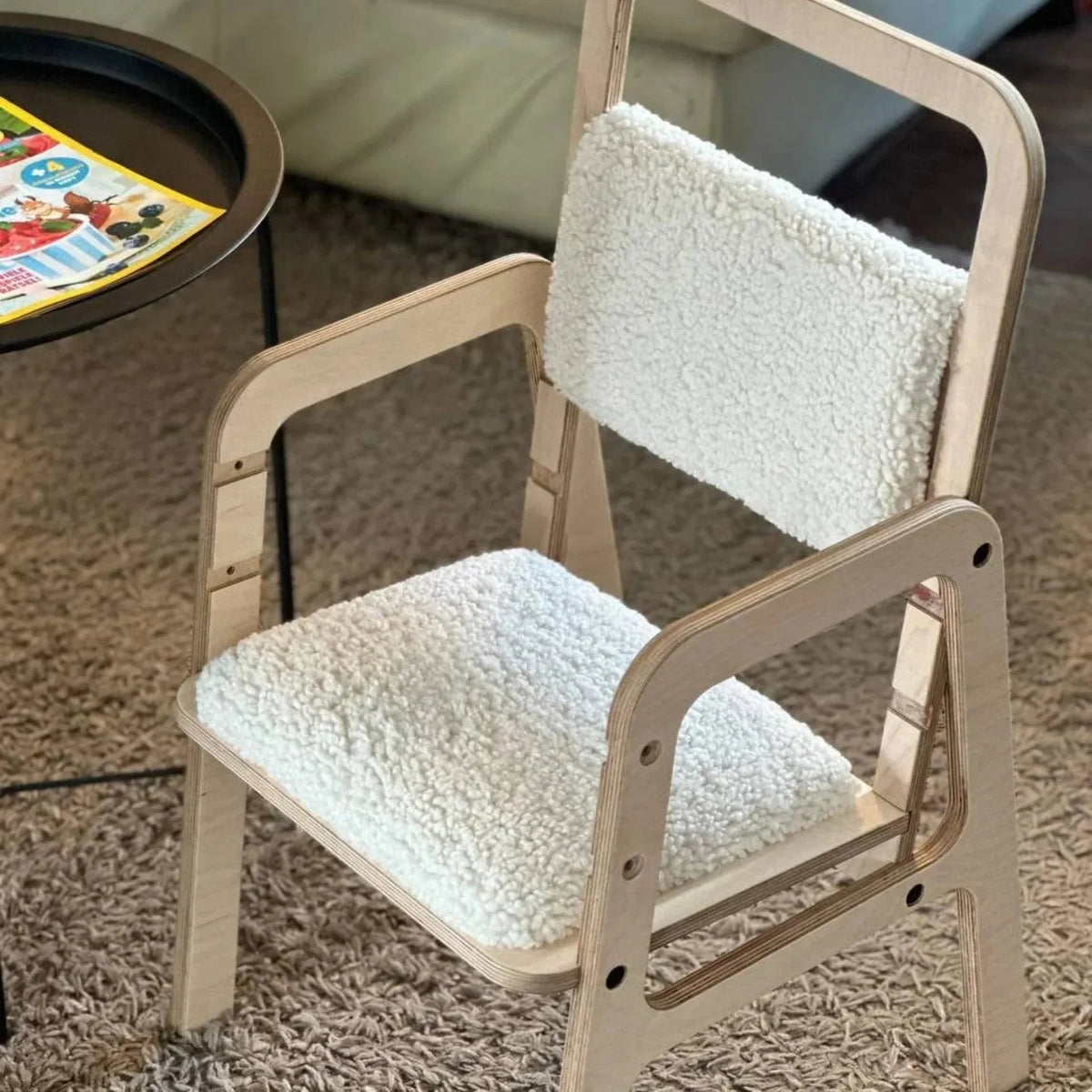 Wooden chair with white cushioned seat and backrest on a carpeted floor.