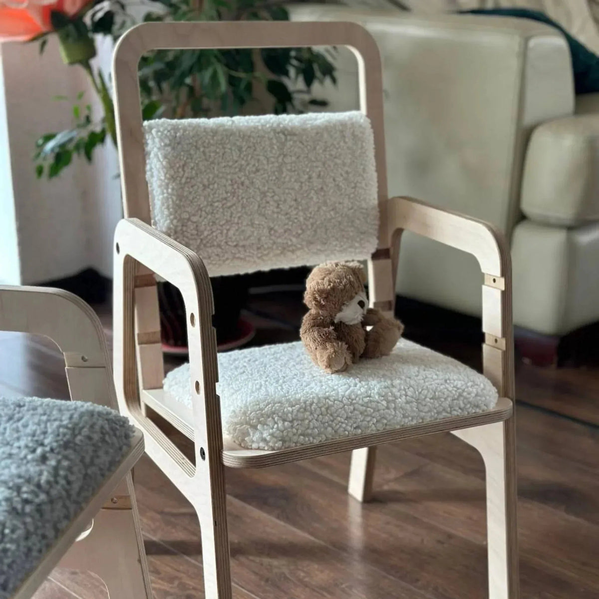 Children's chair with a teddy bear on a wooden floor in a room setting.
