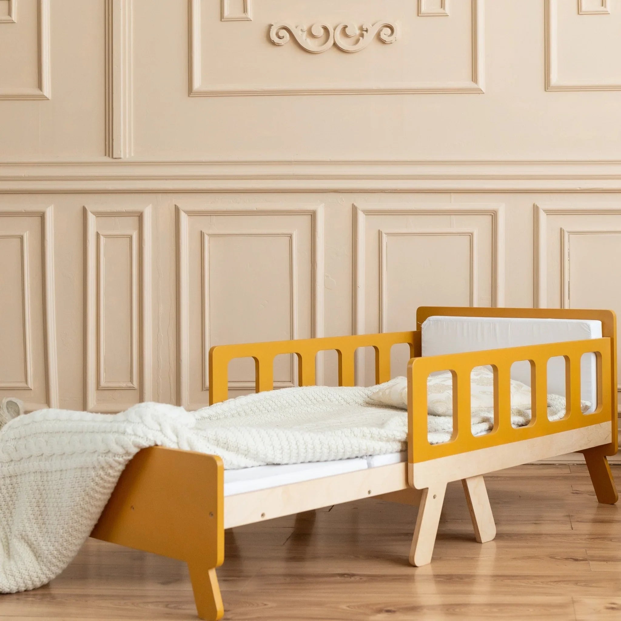 Montessori-inspired wooden kids bed with yellow railings and cozy bedding in a stylish room