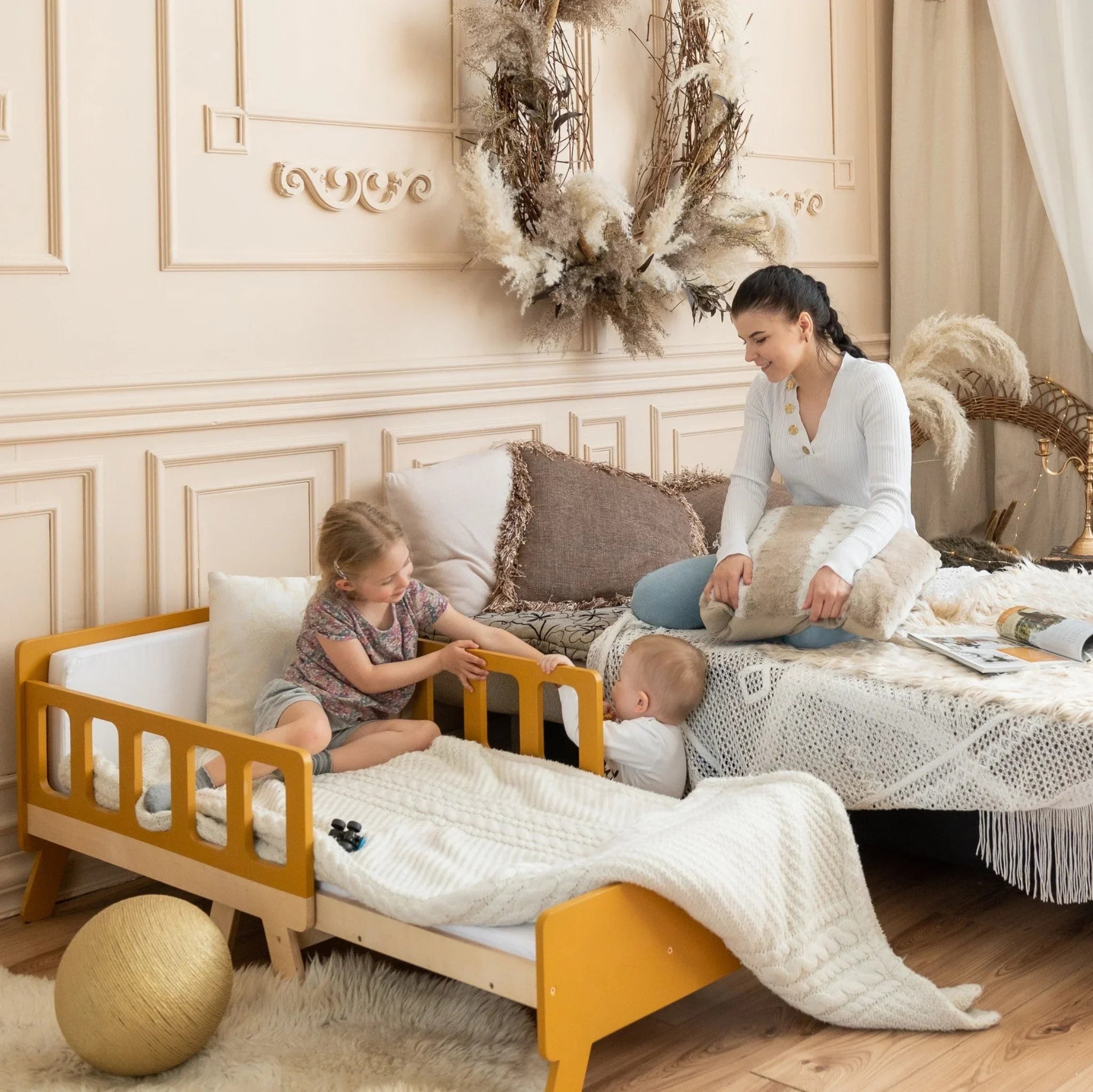 Montessori toddler bed with side rails in cozy kids room with children and parent