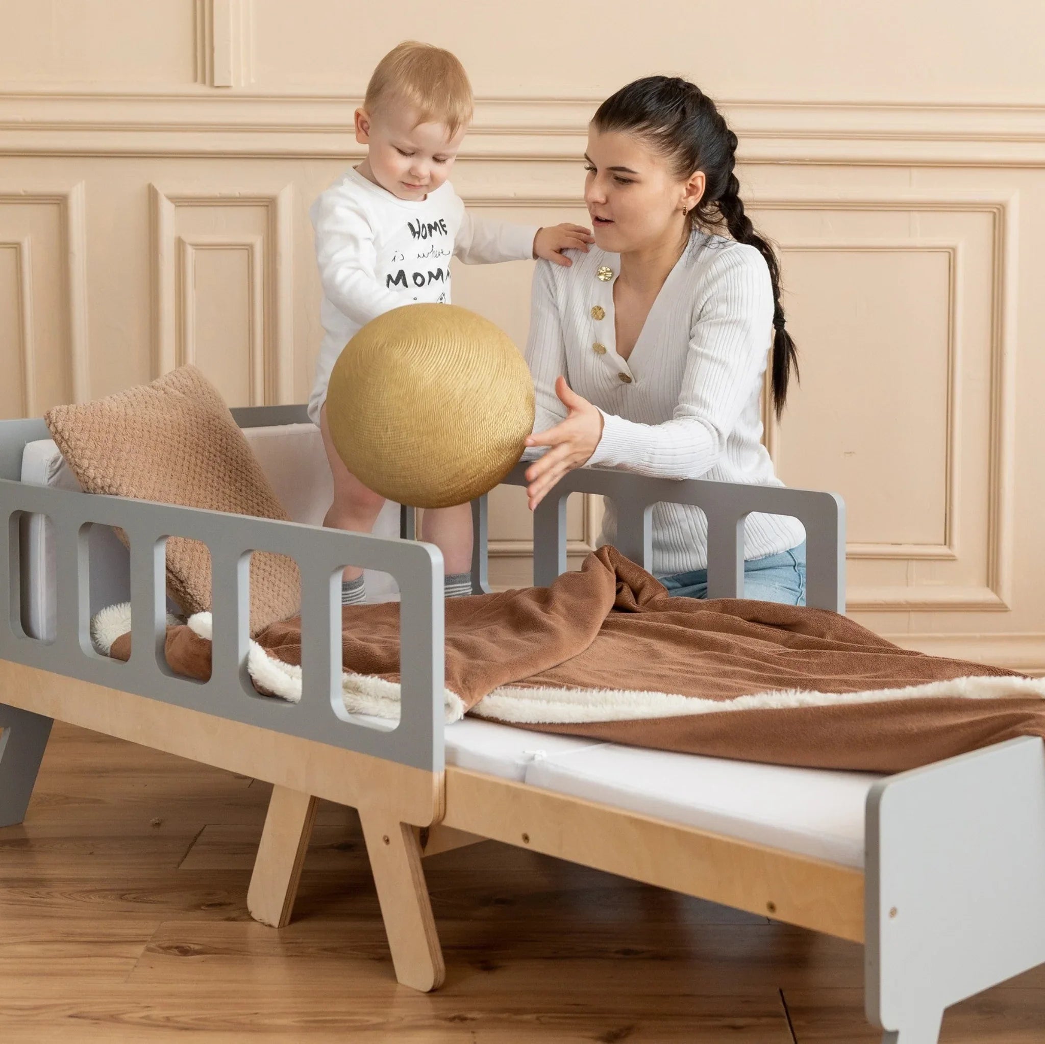 Montessori toddler bed with rails, cozy bedding, child and adult playing in calm kids’ room