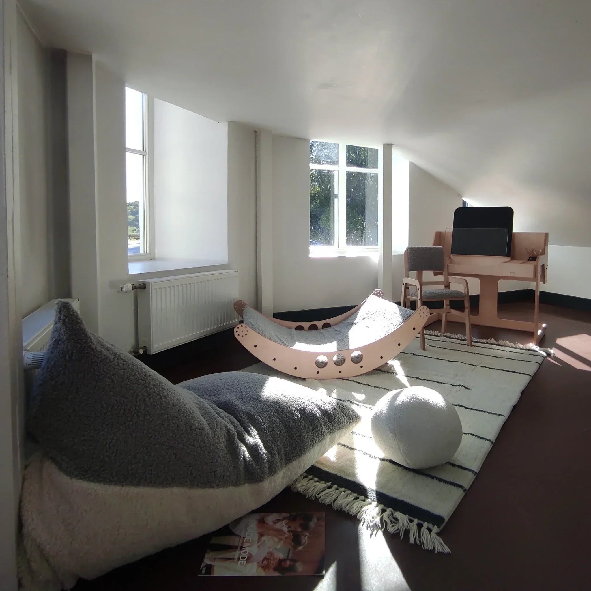 Kids' bean bag chair and wooden play furniture in a bright, modern playroom with natural light