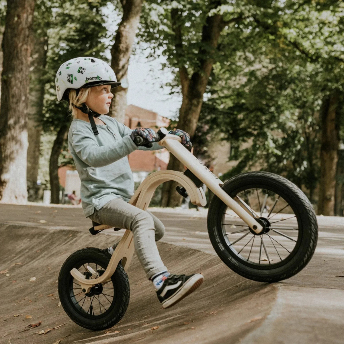 Child riding a balance bike on a wooden path with trees in the background