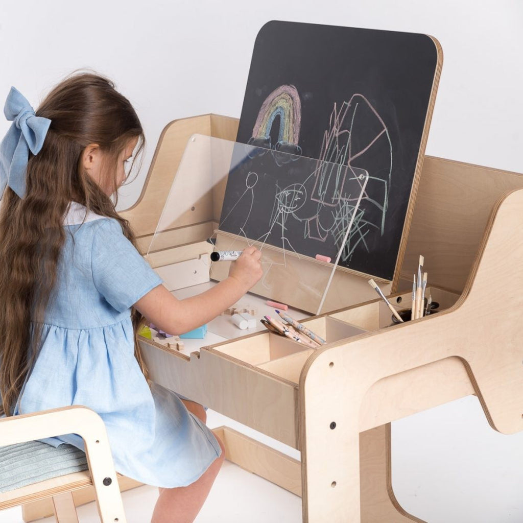 Child drawing at Montessori-inspired wooden art desk with chalkboard and art supplies